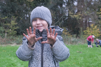 Young boy showing his muddy hands after planting trees