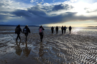 Group walking on beach at sunset