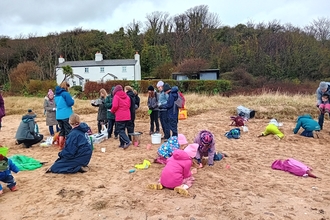 People gathered on a beach looking at the items found in the strandline.
