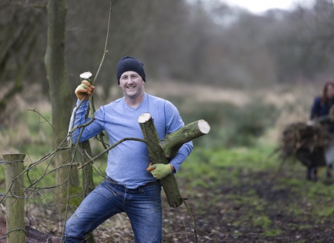 Volunteer carrying wood at Bagmere